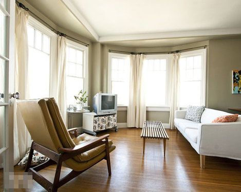 六扇大窗户环绕客厅。简约的白色沙发、木地板带着浓浓的北欧风格