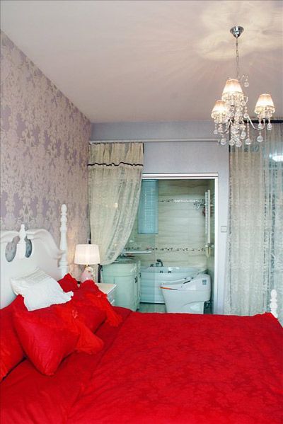 在晶莹剔透的水晶吊灯映射下，欧式床与红色蕾丝床品，粉紫色墙纸与蕾丝门帘，将卧室营造出甜美暧昧的情调