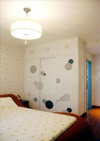 卧室的另一面是线条自然顺畅的三门衣柜，大小不一的圆点花纹简单而活泼，优雅的展现出主人非凡的气质