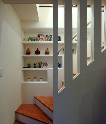 通往三楼的楼梯处，在墙壁内部进行装饰，用头重脚轻的阶梯式内陷置物层和楼梯相互映衬，增加视觉的层次感。同时内陷的置物层能收纳、摆放物品之外，还能节省空间