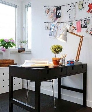 黑色的书桌与地板的颜色相协调。墙边上的低柜上的粉红色的小花，透着春的芬芳