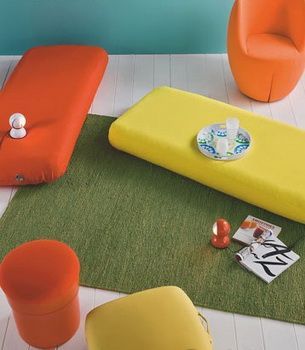 立体塑形设计的布艺坐具，以时装界今年大热的三文鱼红和鲜柠黄色，带出随意的潮流感。草绿色地毯中和了艳色的表现，制造出清凉感