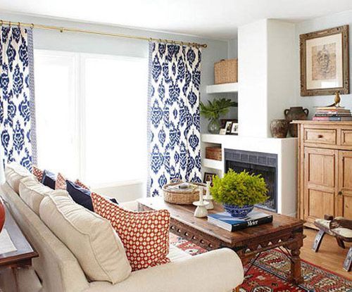 蓝色印花图案的窗帘很出彩，搭配室内的暗红色以及原木家具、米白色棉麻沙发，让空间质感个更为突出